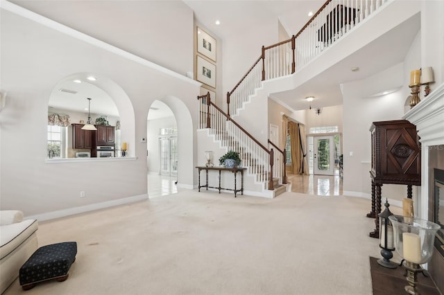 entryway with a high ceiling, arched walkways, stairs, carpet, and baseboards