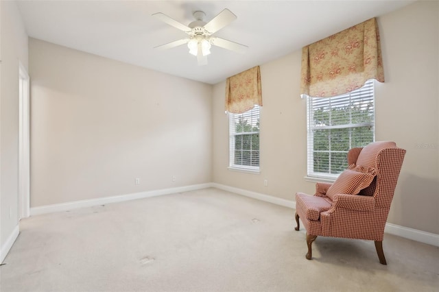 living area featuring light carpet, baseboards, and a ceiling fan