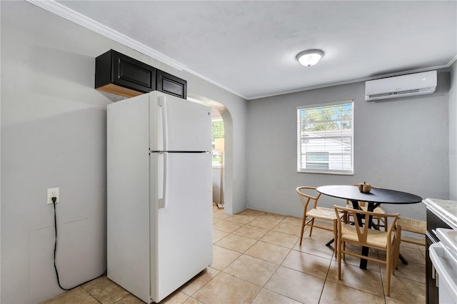 kitchen with freestanding refrigerator, a wall mounted AC, arched walkways, dark cabinets, and light tile patterned floors
