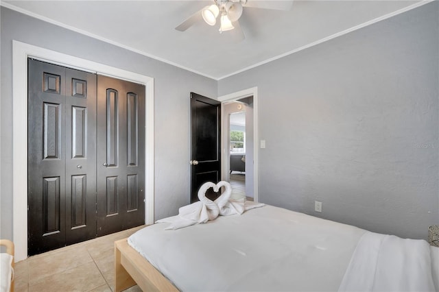 bedroom featuring ornamental molding, a closet, light tile patterned floors, and a ceiling fan