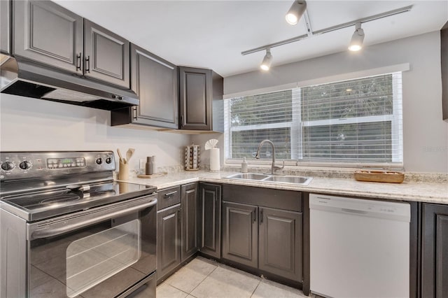 kitchen with white dishwasher, electric stove, a sink, under cabinet range hood, and light tile patterned floors