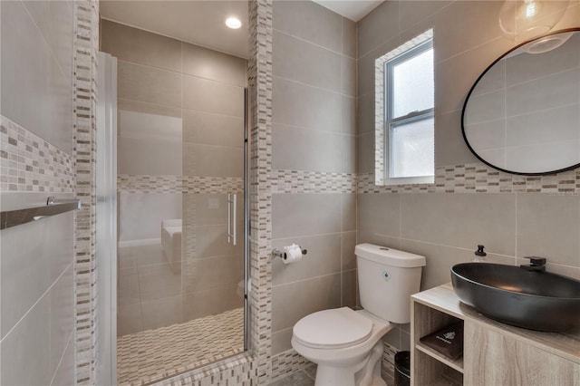 bathroom featuring tile walls, a stall shower, toilet, and vanity