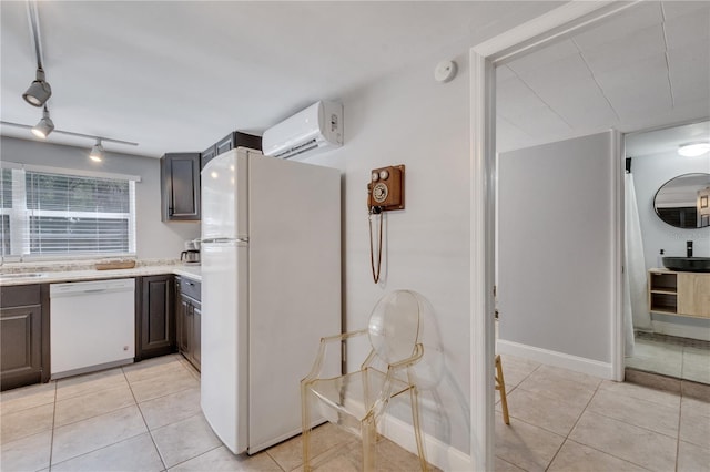 kitchen with white appliances, a wall mounted AC, light tile patterned floors, and light countertops