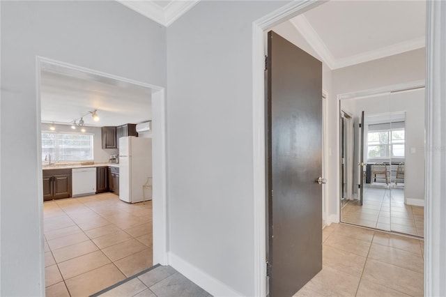 hallway with light tile patterned flooring, ornamental molding, a sink, and baseboards