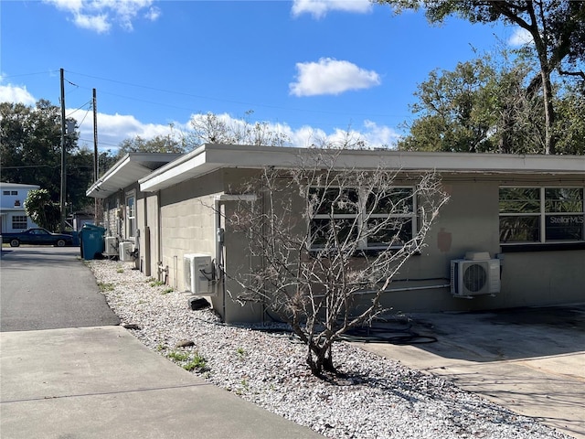 view of property exterior with concrete block siding and ac unit