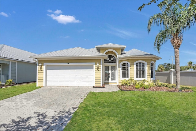 ranch-style house with french doors, decorative driveway, metal roof, a front lawn, and a garage