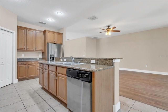 kitchen with appliances with stainless steel finishes, a sink, light tile patterned floors, a ceiling fan, and a kitchen island with sink