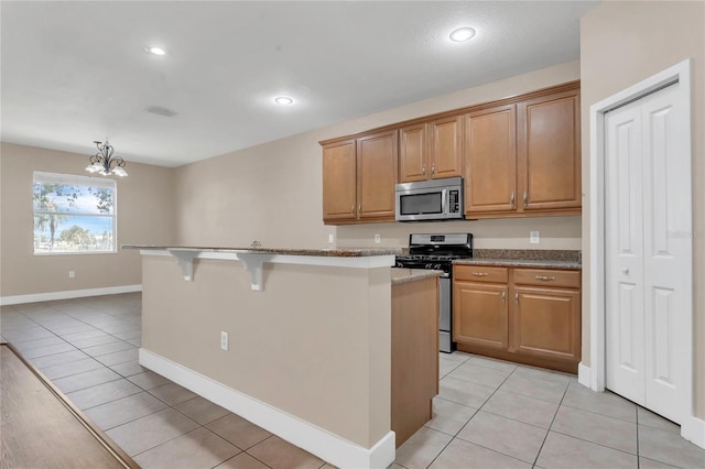 kitchen with stainless steel appliances, light tile patterned flooring, a breakfast bar area, a chandelier, and recessed lighting
