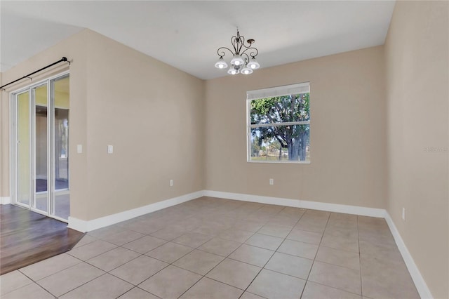 spare room with light tile patterned flooring, baseboards, and a chandelier