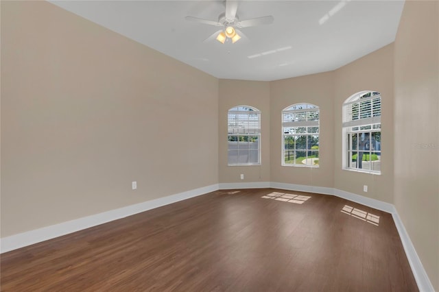 unfurnished room featuring dark wood-style floors, a ceiling fan, and baseboards