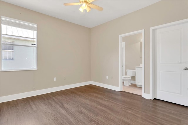 unfurnished bedroom featuring wood finished floors, baseboards, ensuite bathroom, and ceiling fan