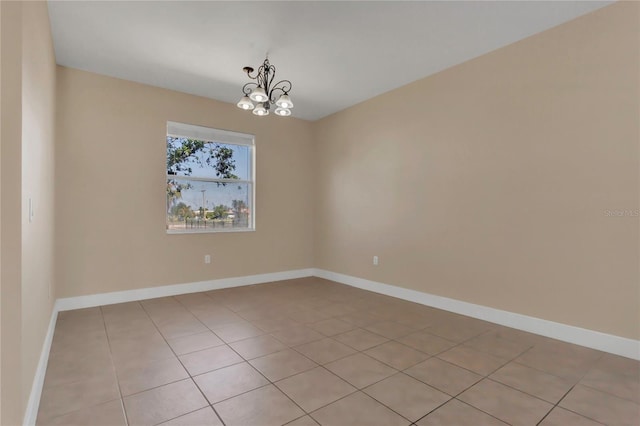 spare room featuring a chandelier, light tile patterned floors, and baseboards