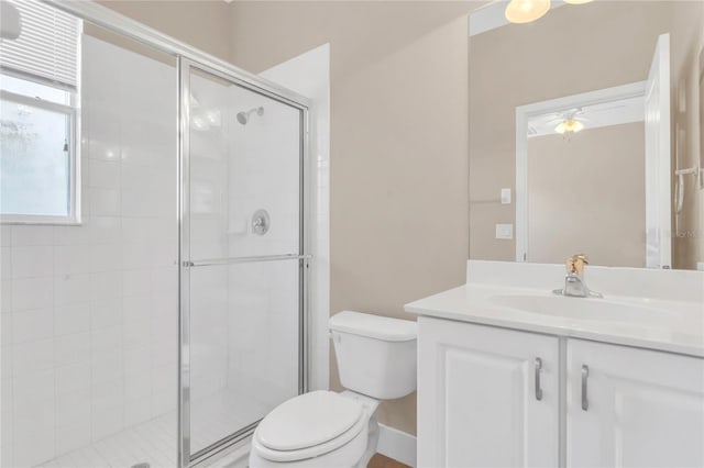 full bathroom featuring a stall shower, toilet, vanity, and a ceiling fan
