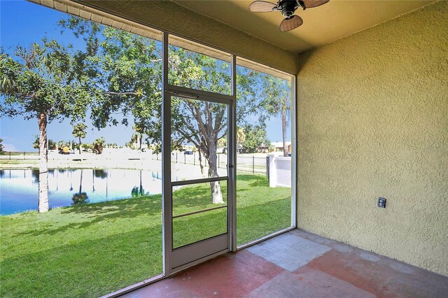 unfurnished sunroom with ceiling fan and a water view