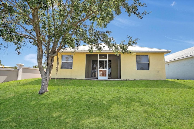 back of property featuring stucco siding and a yard