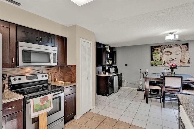 kitchen with stainless steel appliances, decorative backsplash, light tile patterned floors, and dark brown cabinetry