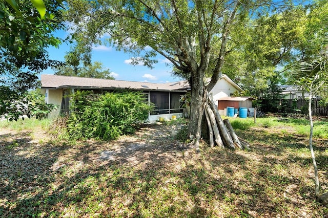 view of yard featuring a sunroom, a shed, an outdoor structure, and fence