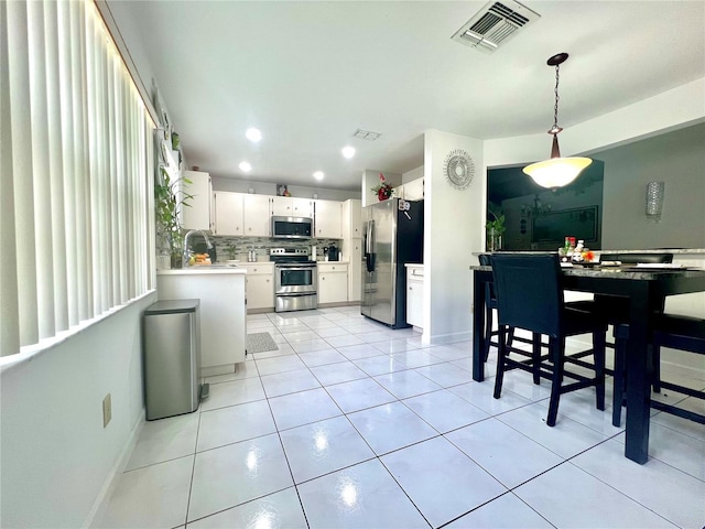 2376 Flamingo Lakes Dr, Kissimmee, FL 34743 - kitchen with stainless steel appliances, light countertops, decorative backsplash, white cabinets, and light tile patterned flooring