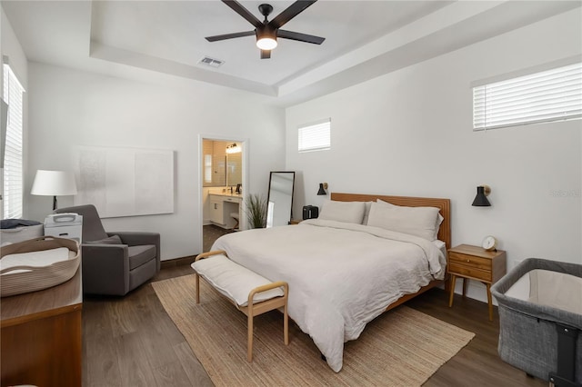 15408 Lebeau Loop, Winter Garden, FL 34787 - bedroom featuring a tray ceiling, wood finished floors, ceiling fan, baseboards, and ensuite bath