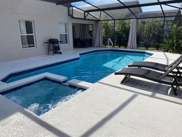 view of swimming pool featuring a patio area, a pool with connected hot tub, grilling area, and glass enclosure