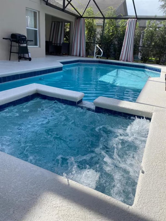view of pool with a pool with connected hot tub, a lanai, and a patio area