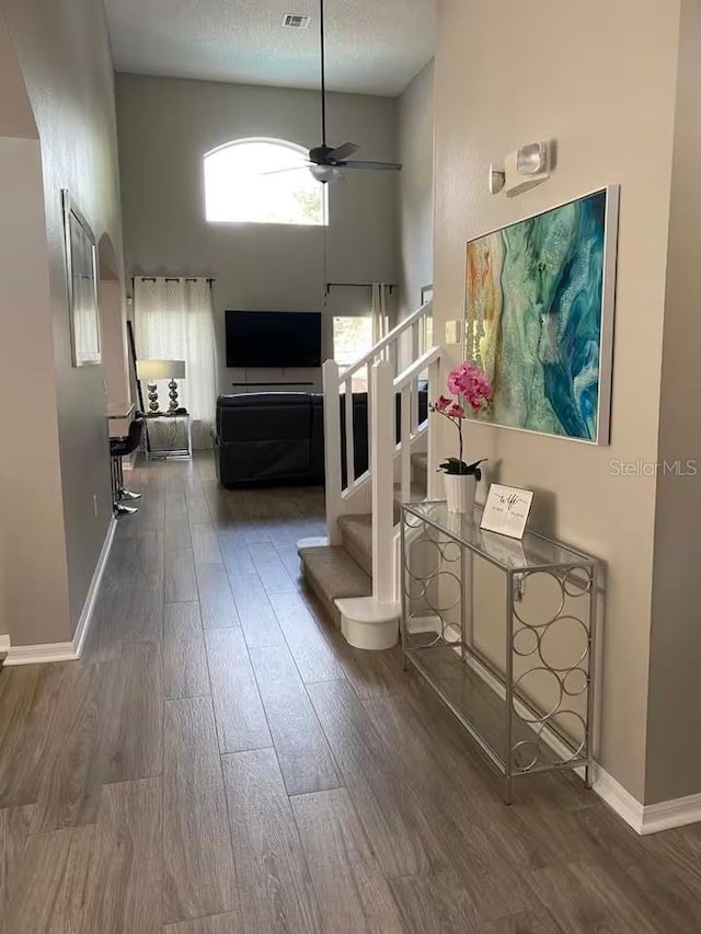 hallway featuring stairway, wood finished floors, baseboards, and a towering ceiling
