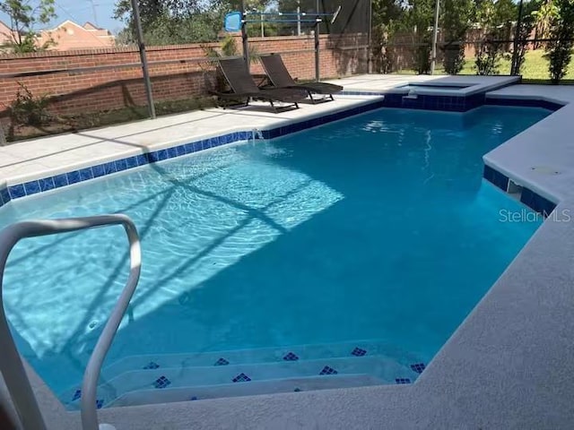 view of swimming pool with a lanai, a patio, a pool with connected hot tub, and fence