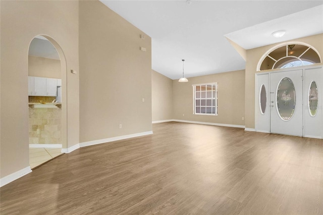 922 Hatteras Ave, Minneola, FL 34715 - foyer with wood finished floors, vaulted ceiling, washer and clothes dryer, baseboards, and plenty of natural light
