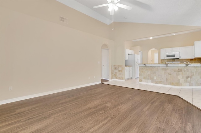 922 Hatteras Ave, Minneola, FL 34715 - unfurnished living room with arched walkways, lofted ceiling, a ceiling fan, light wood-style flooring, and baseboards