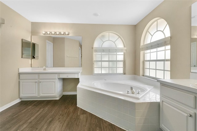 922 Hatteras Ave, Minneola, FL 34715 - bathroom featuring wood finished floors, a bath, two vanities, and baseboards