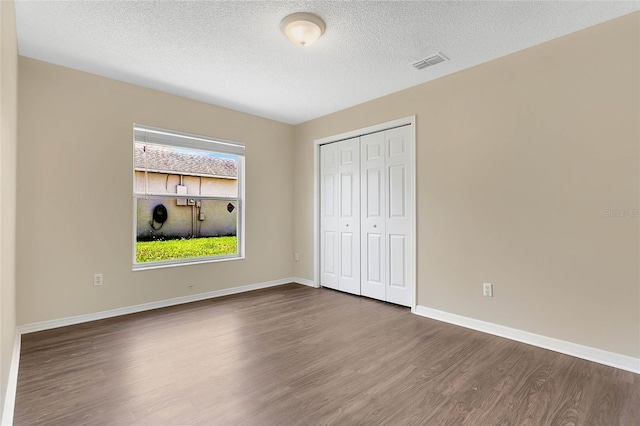 922 Hatteras Ave, Minneola, FL 34715 - unfurnished bedroom with wood finished floors, a closet, a textured ceiling, and baseboards