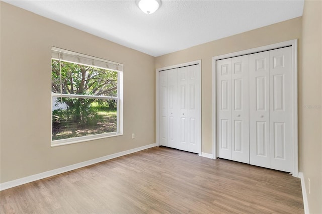 922 Hatteras Ave, Minneola, FL 34715 - unfurnished bedroom with light wood-style floors, two closets, and baseboards