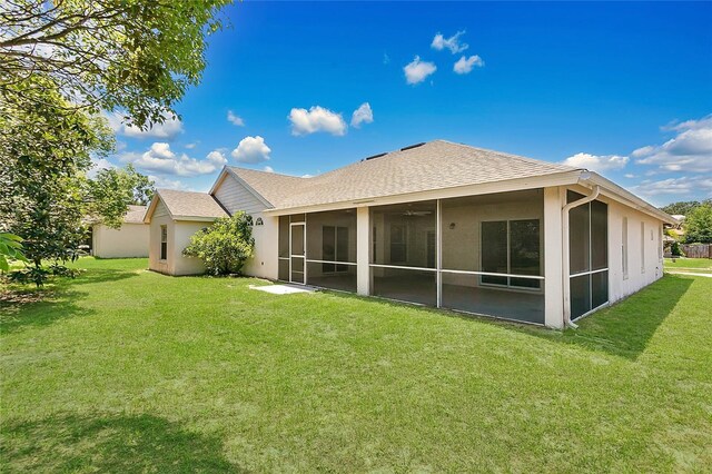 922 Hatteras Ave, Minneola, FL 34715 - rear view of house with a sunroom, a lawn, roof with shingles, and stucco siding
