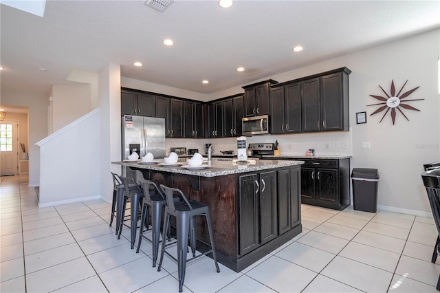 9038 Sunshine Ridge Loop, Kissimmee, FL 34747 - kitchen with stainless steel appliances, a kitchen bar, recessed lighting, light tile patterned flooring, and baseboards