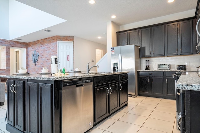 9038 Sunshine Ridge Loop, Kissimmee, FL 34747 - kitchen featuring appliances with stainless steel finishes, a kitchen island with sink, light stone countertops, light tile patterned floors, and recessed lighting