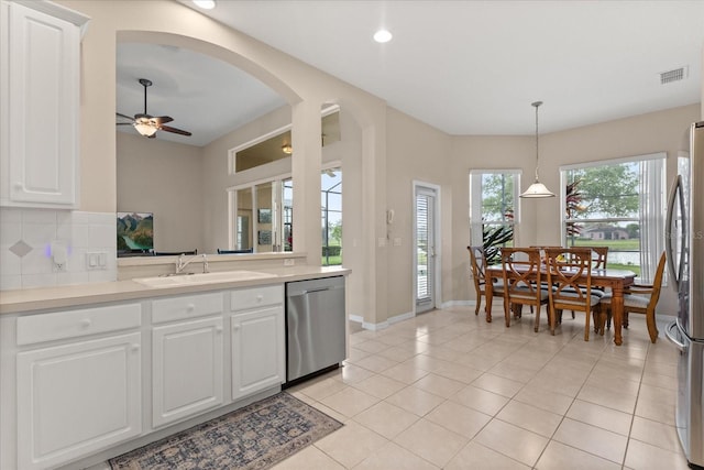 14174 Islamorada Dr, Orlando, FL 32837 - kitchen featuring stainless steel appliances, a sink, arched walkways, light tile patterned flooring, and white cabinetry