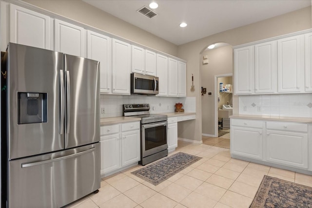 14174 Islamorada Dr, Orlando, FL 32837 - kitchen featuring appliances with stainless steel finishes, white cabinetry, arched walkways, and recessed lighting