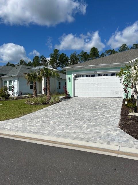 867 Bama Breeze Dr, Daytona Beach, FL 32124 - view of front of property with decorative driveway, an attached garage, and a front lawn
