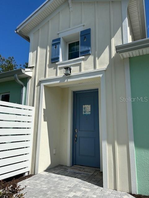 867 Bama Breeze Dr, Daytona Beach, FL 32124 - doorway to property with board and batten siding, stucco siding, and fence