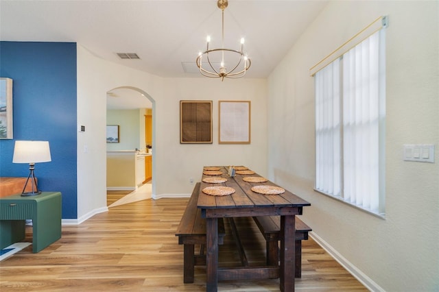 2956 White Cedar Cir, Kissimmee, FL 34741 - dining space with arched walkways, light wood-style flooring, a chandelier, and baseboards