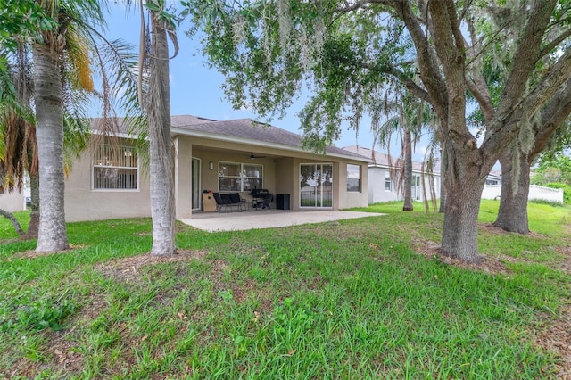 2956 White Cedar Cir, Kissimmee, FL 34741 - back of house featuring stucco siding, ceiling fan, a patio, and a yard
