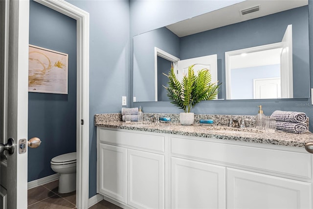 bathroom featuring double vanity, toilet, baseboards, and tile patterned floors