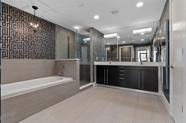 full bathroom with a stall shower, a bath, double vanity, a chandelier, and recessed lighting