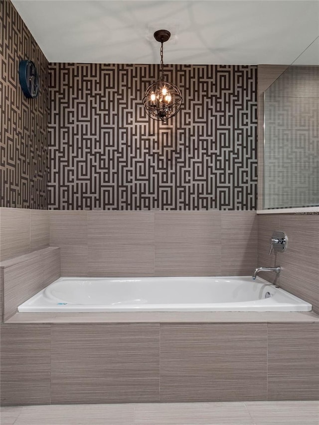 full bath with wallpapered walls, tile patterned flooring, a chandelier, and tiled bath