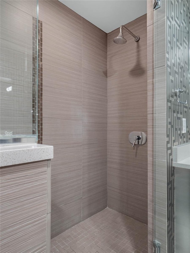 full bath with tiled shower, tile walls, and vanity