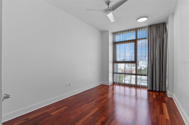 unfurnished room with expansive windows, ceiling fan, dark wood-type flooring, and baseboards