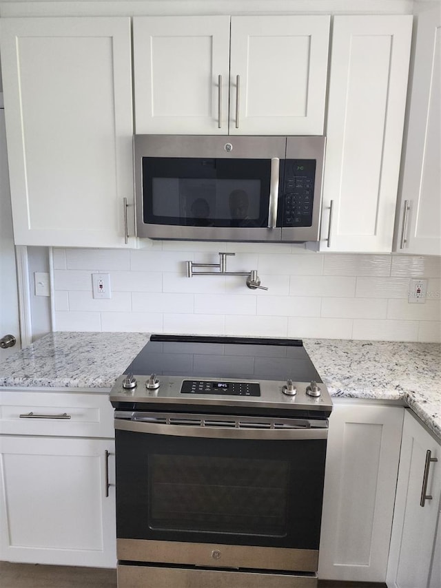 5325 Cocoa Ct, Cape Coral, FL 33904 - kitchen with stainless steel appliances, white cabinetry, backsplash, and light stone countertops