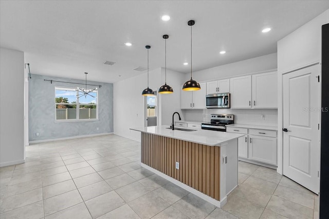 kitchen with stainless steel appliances, a sink, light countertops, a kitchen island with sink, and a chandelier