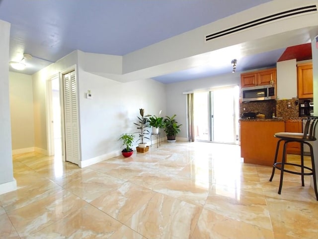 1820 James Ave Unit 2F, Miami Beach, FL 33139 - kitchen featuring stainless steel microwave, light marble finish floors, tasteful backsplash, and baseboards