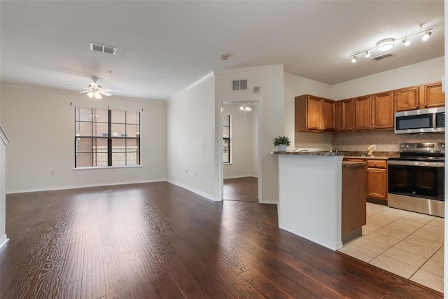 kitchen with appliances with stainless steel finishes, brown cabinetry, light wood-style flooring, decorative backsplash, and a ceiling fan